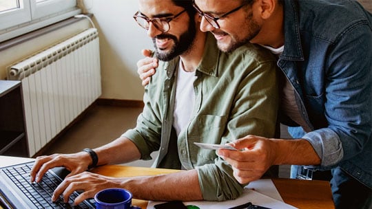 Two smiling men looking at a computer